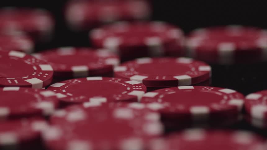 Red and white poker chips sit in stacks on dark surface
