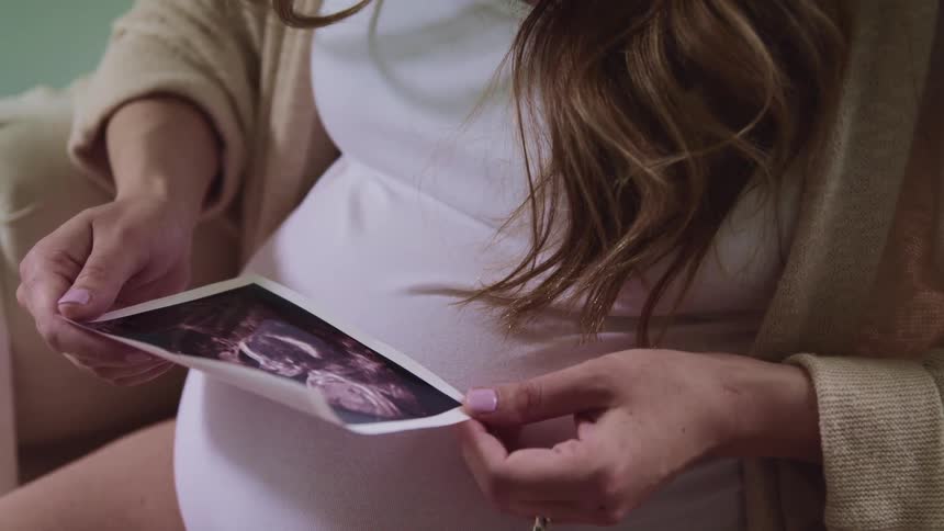 A pregnant woman is looking at a sonogram picture