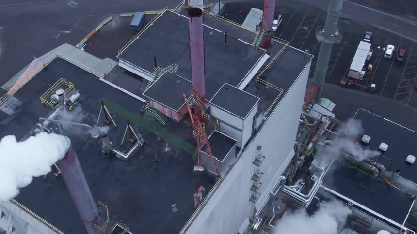 Aerial view of a power plant or factory with white smoke coming out of chimney