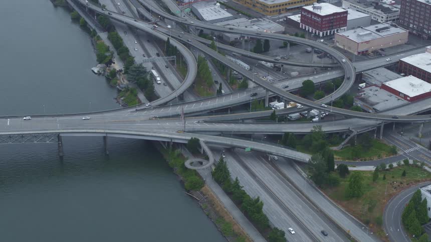 Aerial view of traffic flowing on a highway intersection over a river near the city