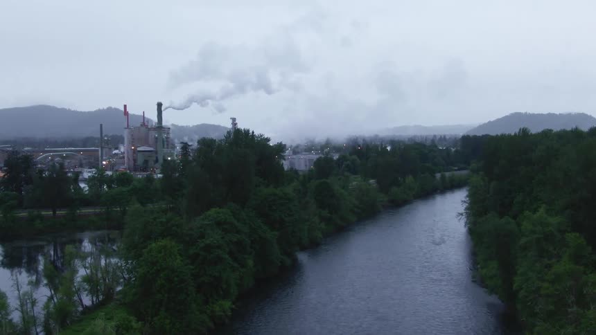 Smoke rises from the factories near the river and forest