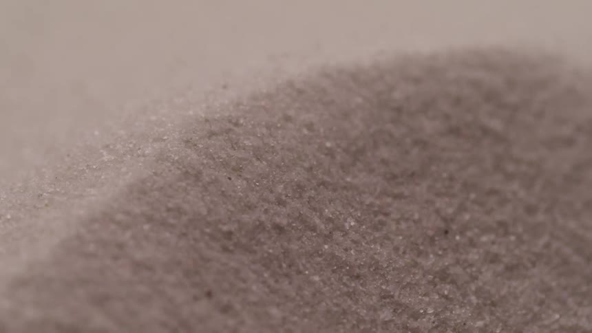 Sand grains rolling over the edge of a small dune blowed by the wind