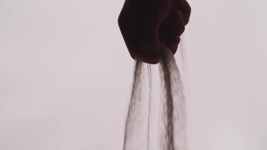 Sand runs through a mans fingers