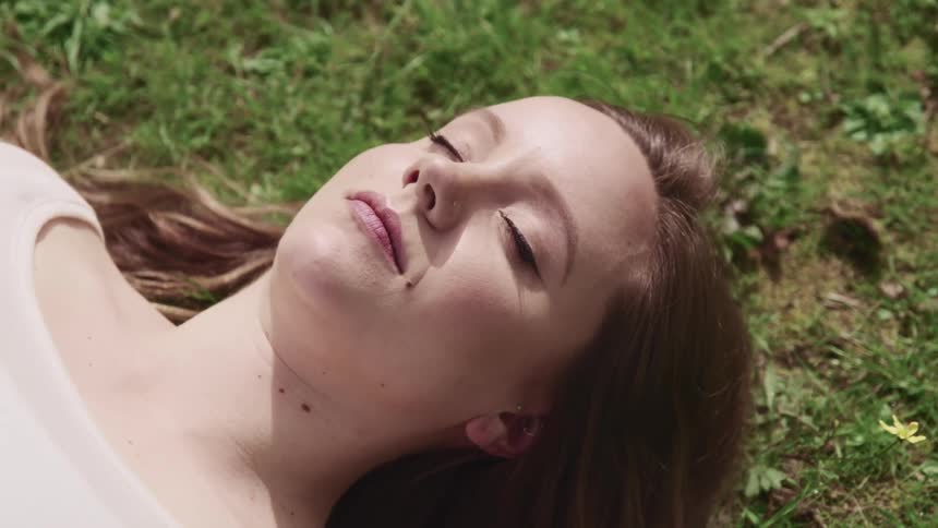 A woman sleeps outside on the grass