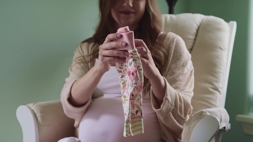 A woman is folding clothes while sitting in the chair