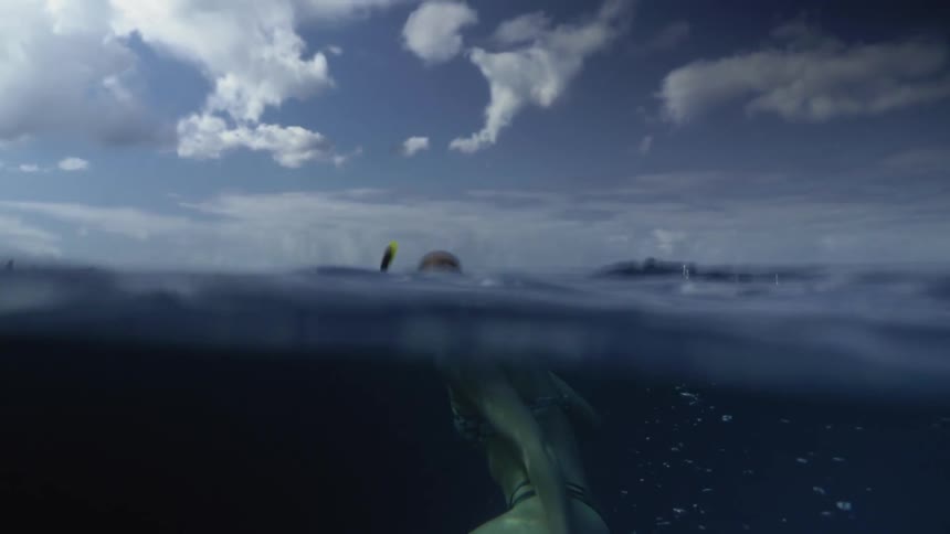 Woman wearing a snorkel swims under the oceans surface