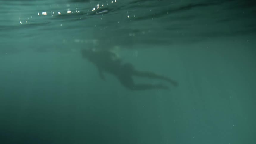 Underwater footage of a person swimming in the green ocean waters