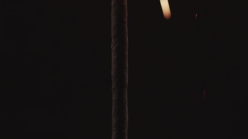 Extreme close up of a sparkler stick showering sparks on a black dark background