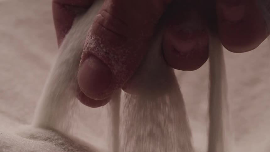A mans hand picks up fine sand