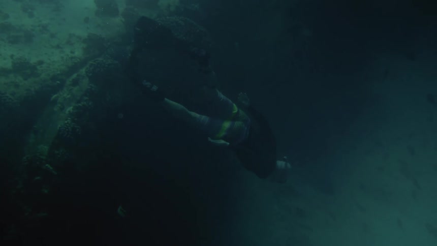 Underwater footage of a man free diving on the green ocean waters