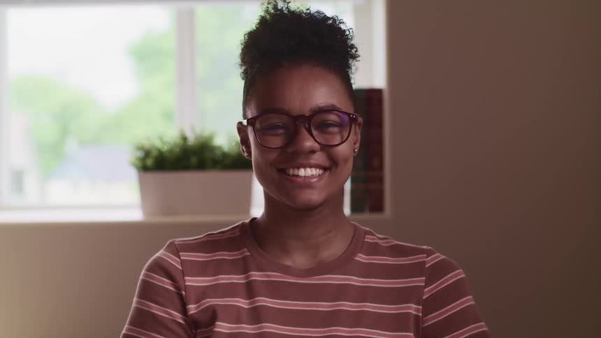 A young woman in eyeglasses smiles into the camera