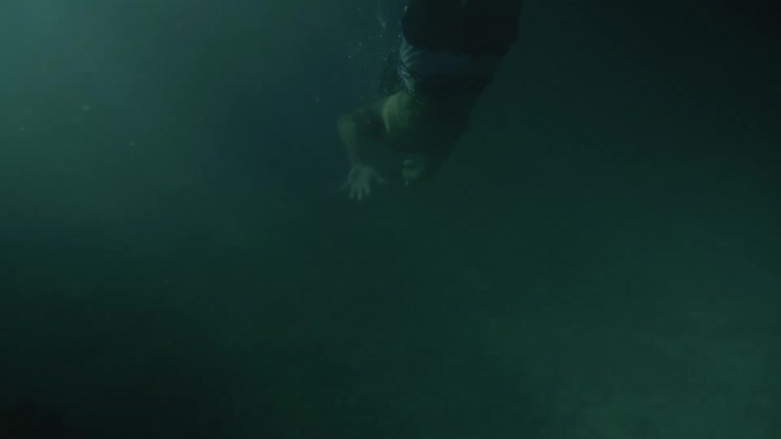 A man dives deep underwater while wearing a snorkel and mask
