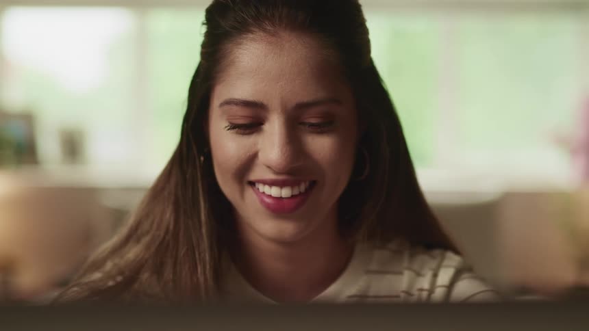 A woman in a striped shirt smiles while sitting indoors