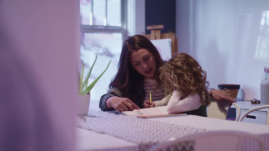 A teacher goes over a worksheet with a young female student
