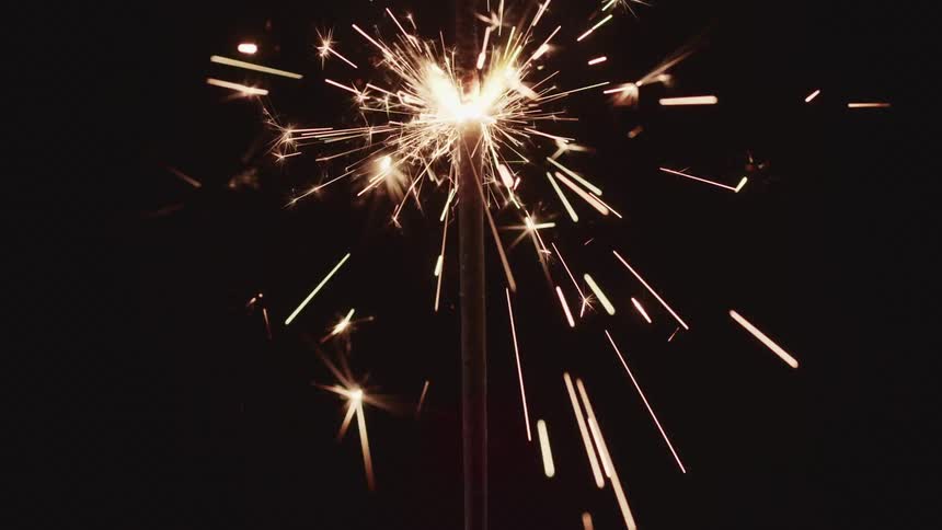 A small sparkling firework rapidly shoots out embers and sparks in a dark environment