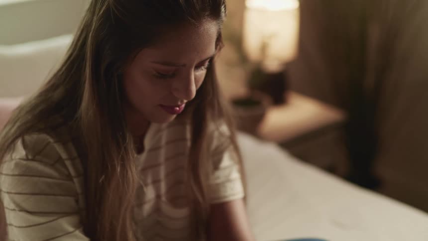 Teenage girl with long hair sits on a bed