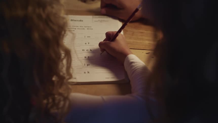 Girl doing homework with a pencil with her mother