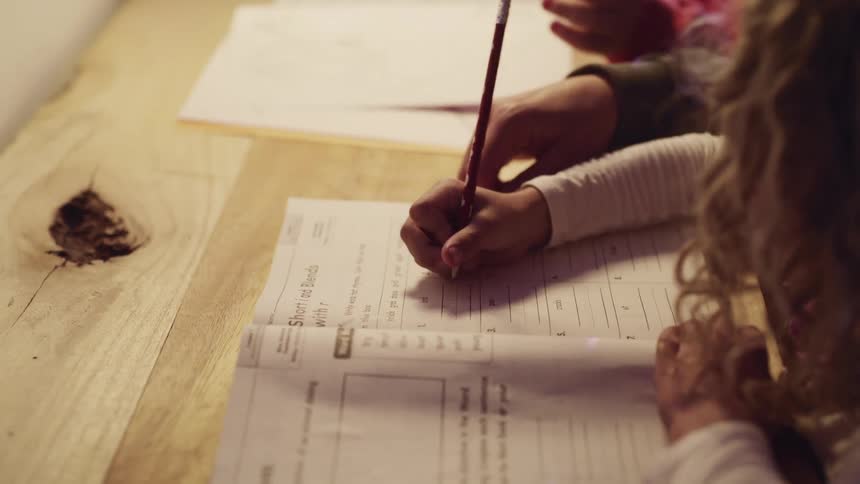 A girl works on homework at a wood table
