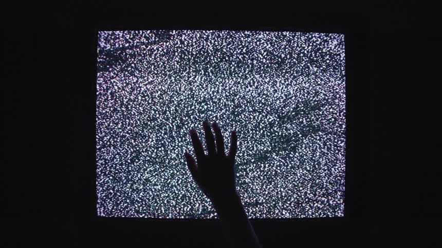 Hand reaches up to put hand on glass front of console showing signal static