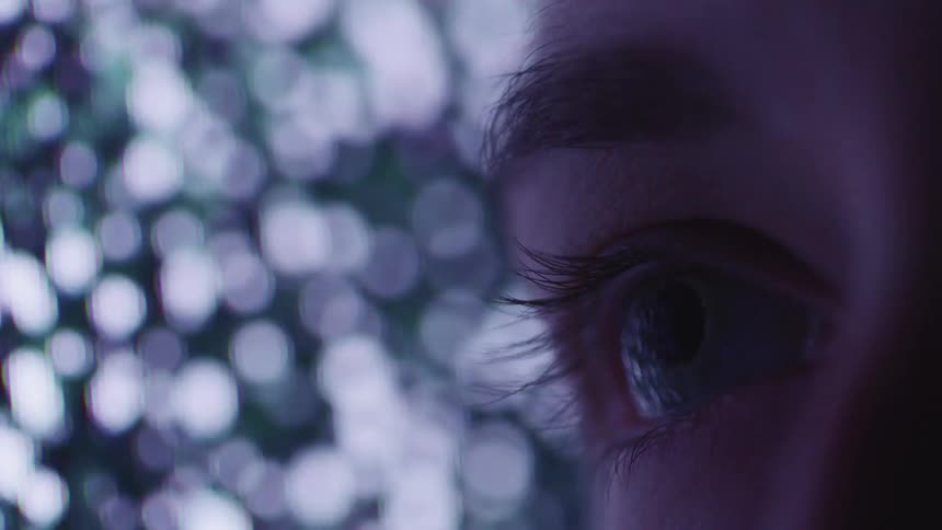 Extreme close up of a womans eye in front of a tv screen showing static