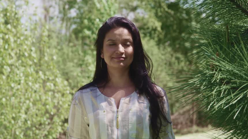 Woman with long hair stands near the trees