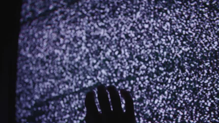 Television shows static while a hand is held up in front of it