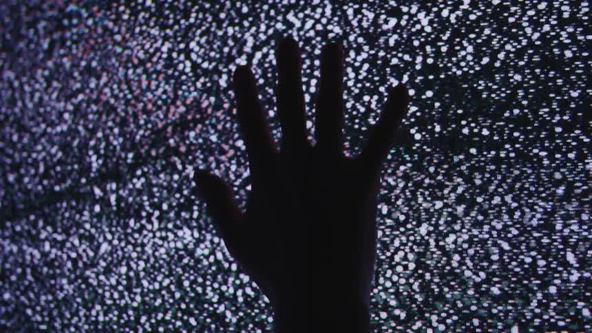 A person is touching a flickering television