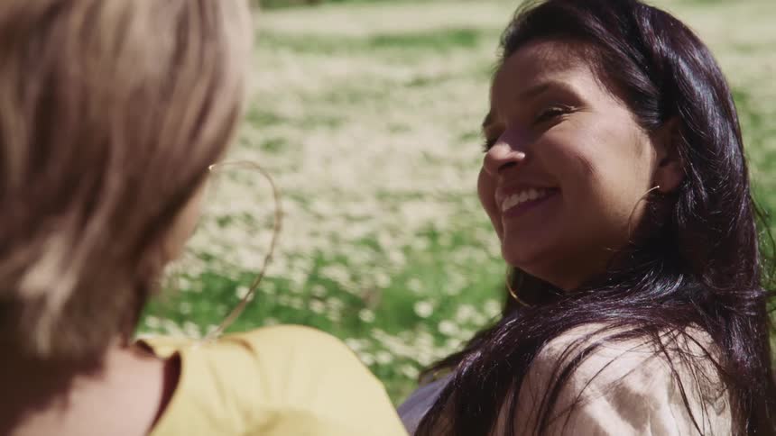 Woman smile at a friend while sitting in the grass
