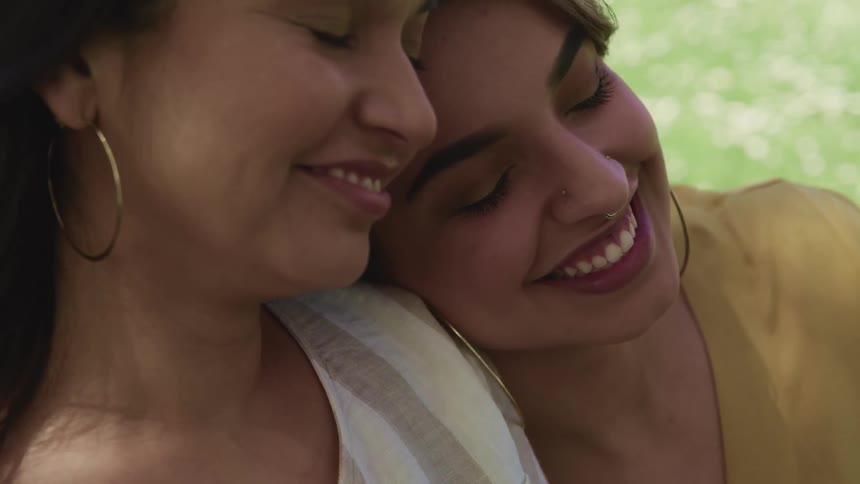 Two women sit close together and smile