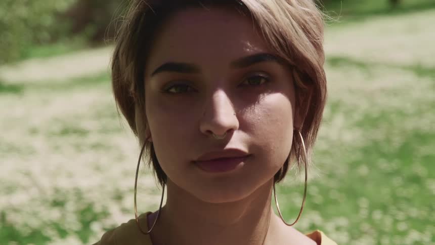 Close up of a young womans face standing in front of a field of wild flowers