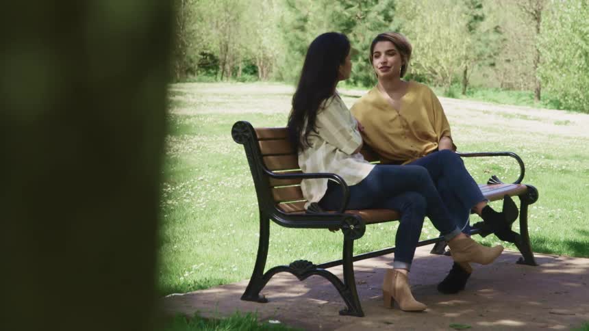 Two women chatting on a bench at a park