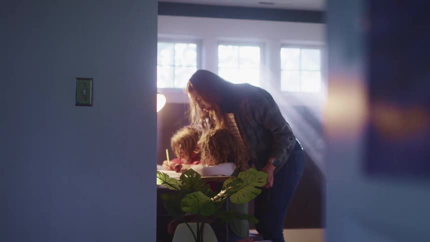 A woman talks with children as they do school work at home