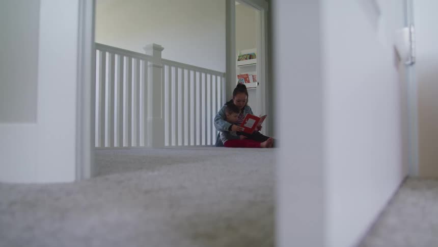 Mother reads to her son as they sit on the floor