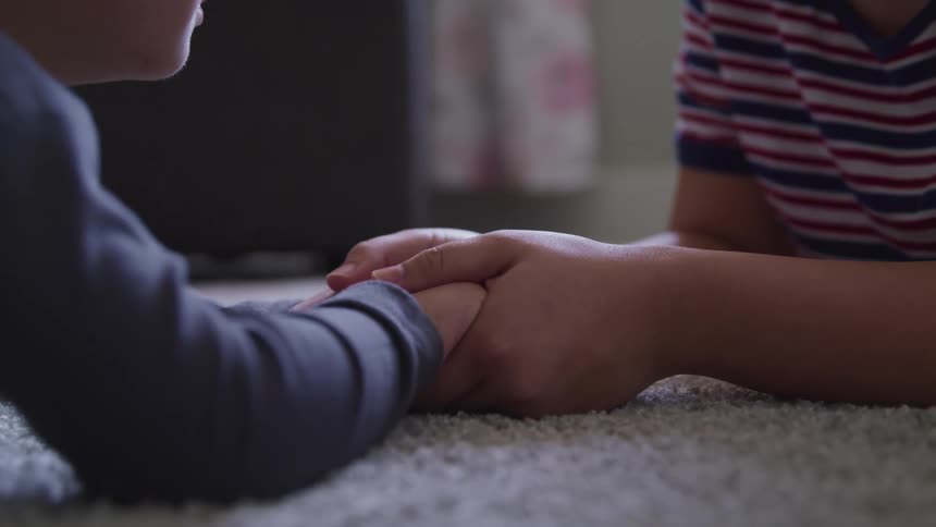 Two children lay on the rug together