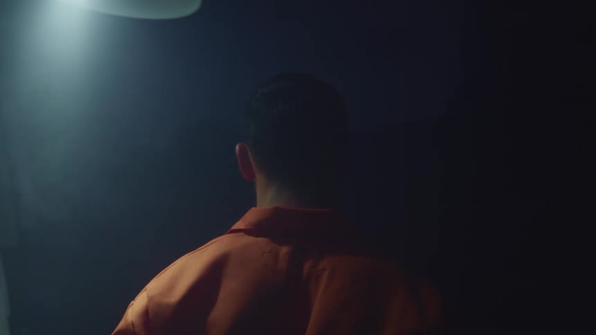 A person stands under a swinging light