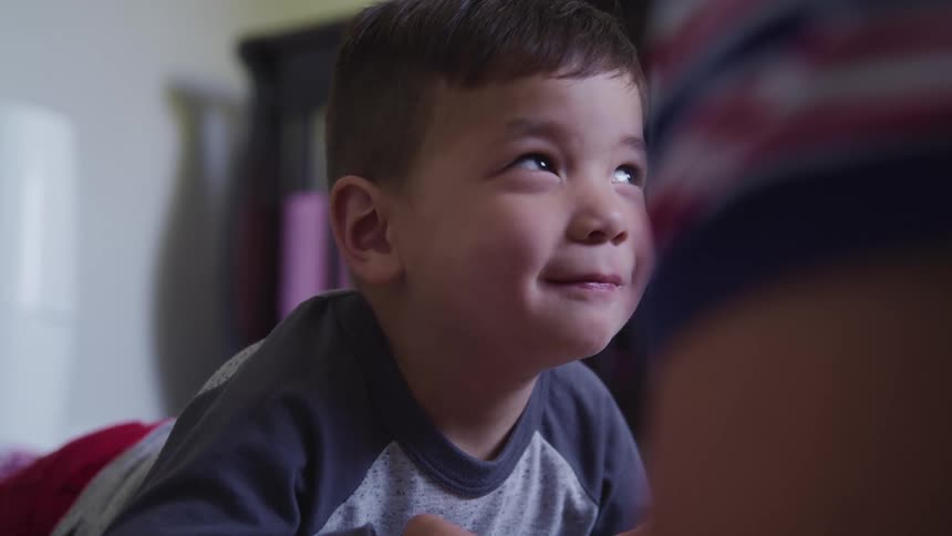 A young boy looks up as he smiles and makes funny faces
