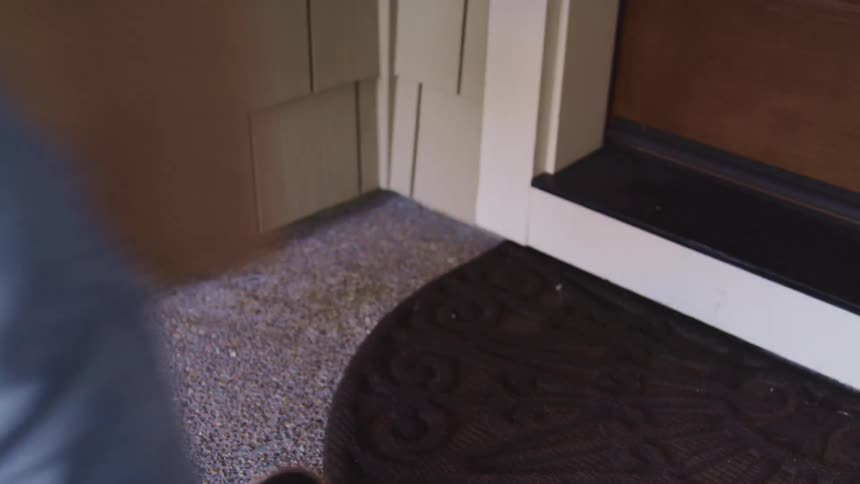 A delivery person picks up a package left on a front stoop