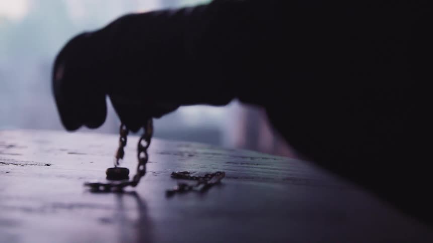 A person lifts the jewelry from the table