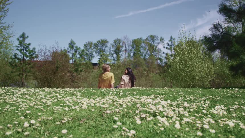 A couple sits on grass and gaze into each others eyes