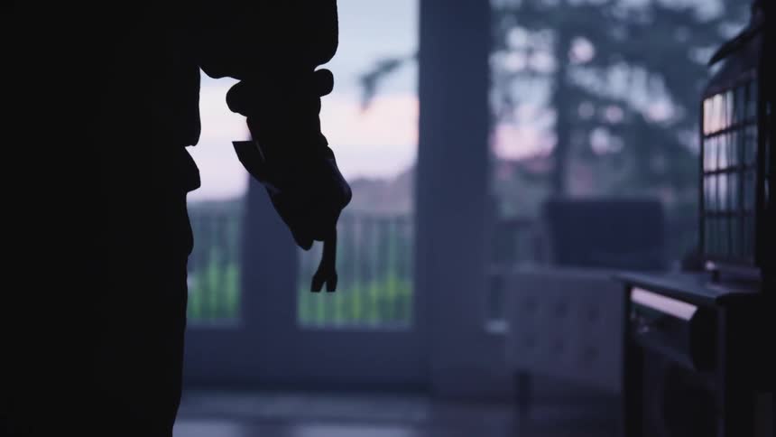 A man holds a hammer in the dark room