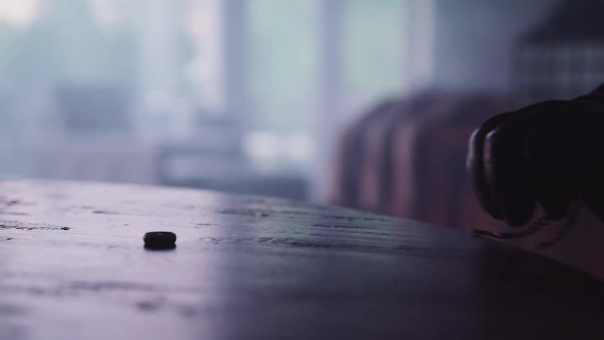 A gloved hand grabs a chain and button off of a table