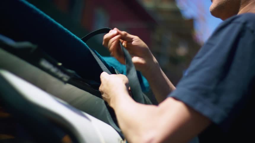 Man adjust straps on roof rack on vehicle