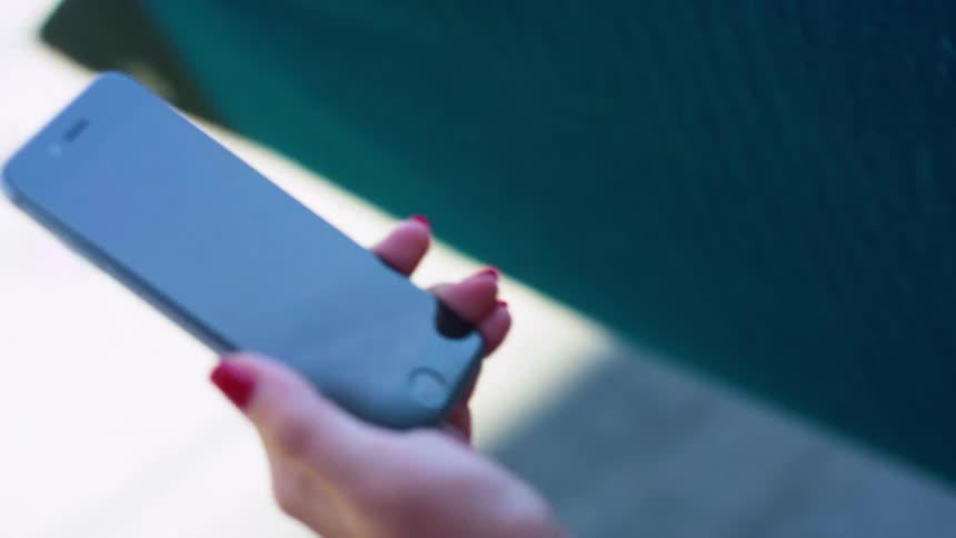 A white woman takes a smartphone out of her pocket