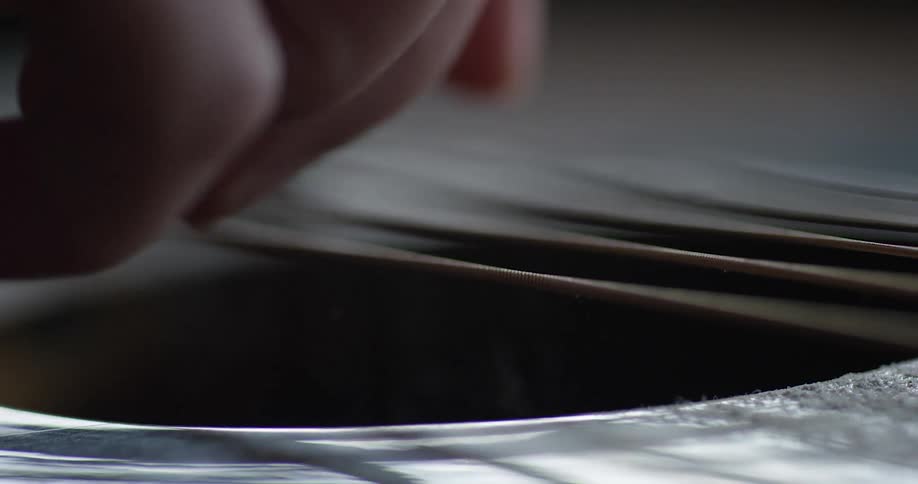 A finger plucks guitar strings