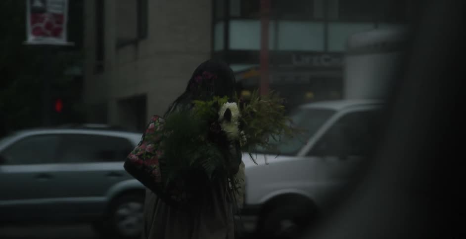A person carrying flowers crosses a street