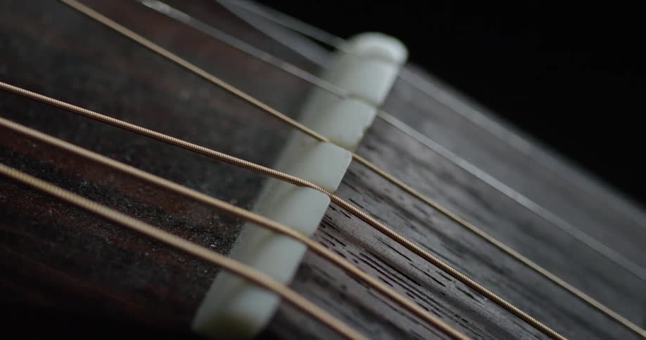 The strings on a musical instrument are threading through the bridge