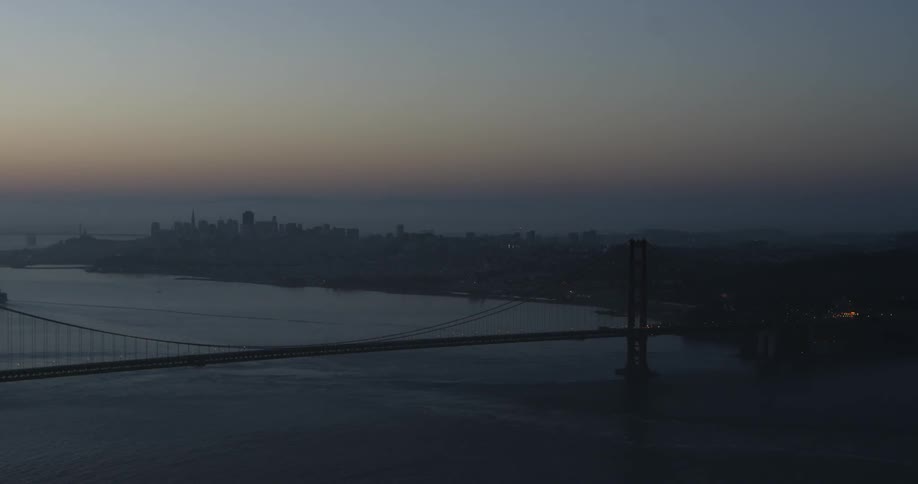 The sun sets over a city and large bridge