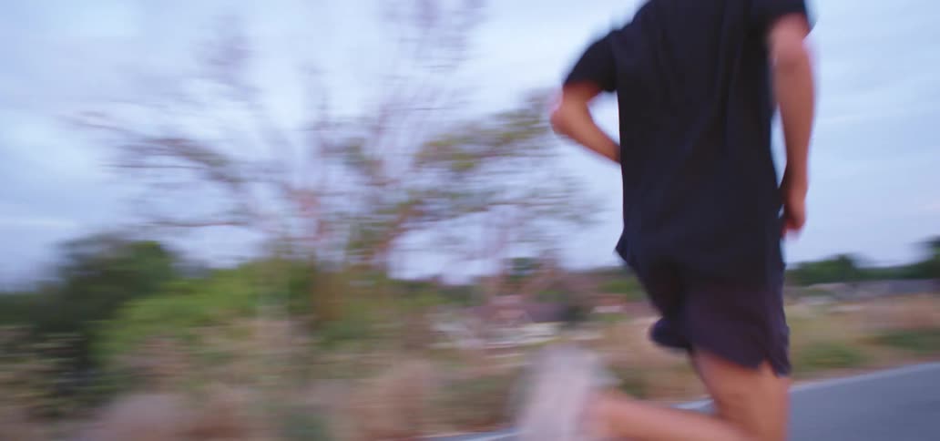 Young man jogging on a road in the country near a wash