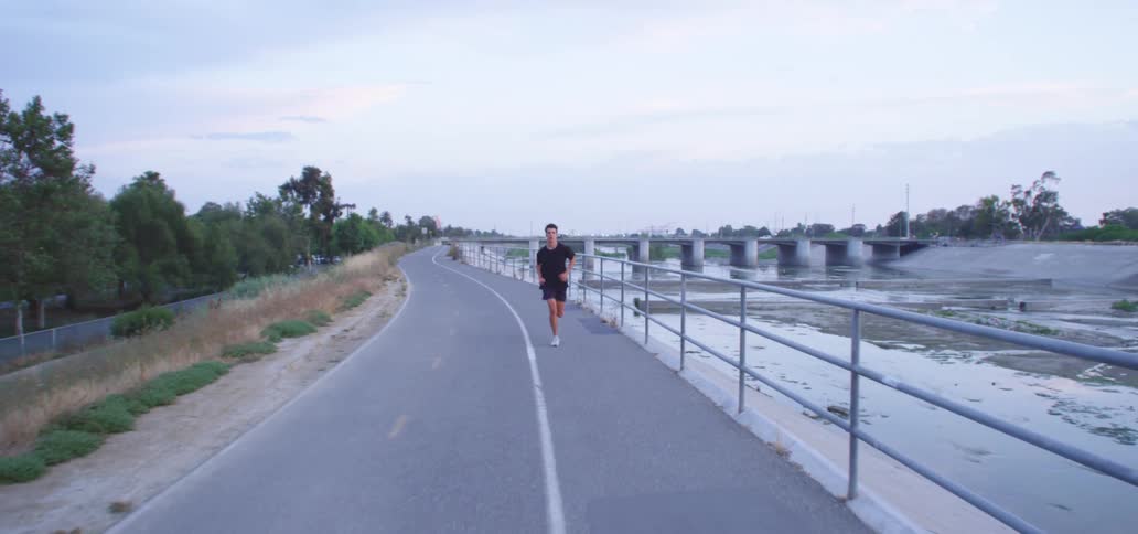Young man jogging on a road near a reservoir