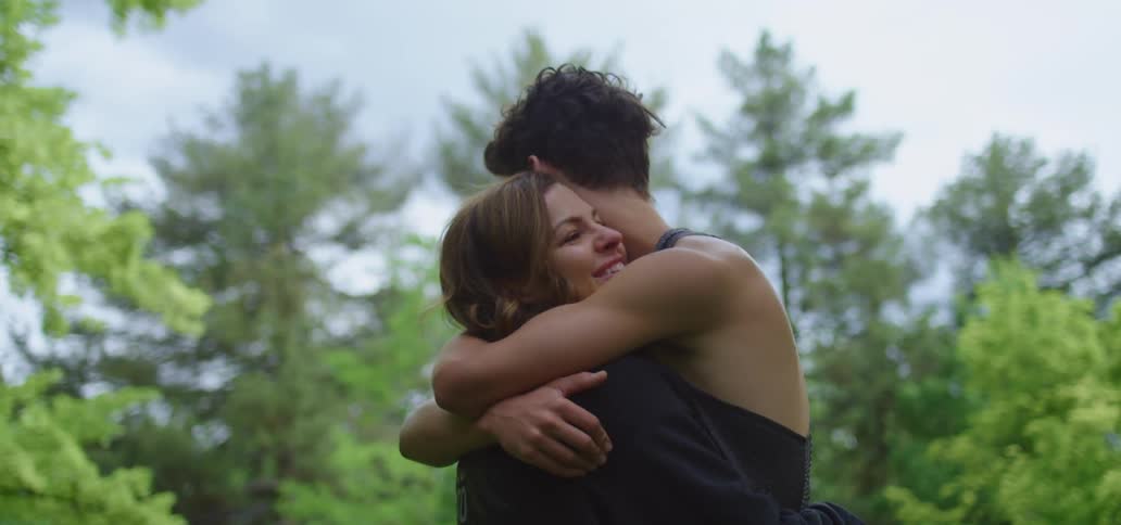 A young man and woman hug outside
